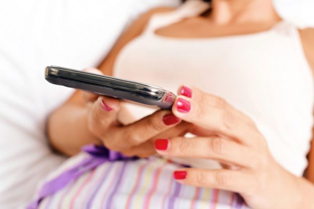 Woman with smart phone in bed