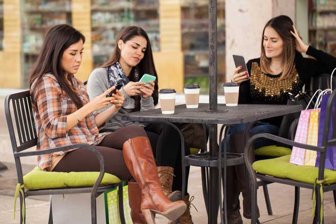 A group of friends ignoring each other and focusing on their smartphones instead